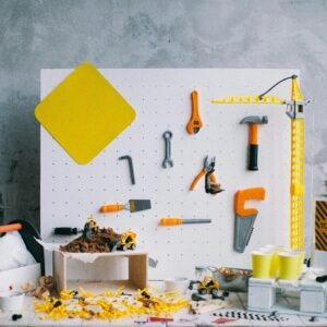 Artistic arrangement of toy tools and construction vehicles on a pegboard backdrop in a workshop setting.